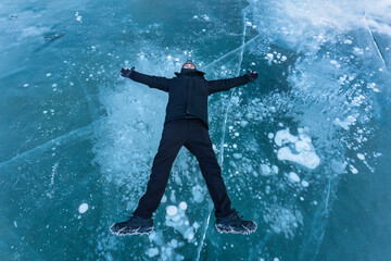 Fototapeta premium Asian male tourist lying and enjoying on frozen lake with natural bubble