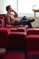 Cheerful young design professional talking on cellphone in his office