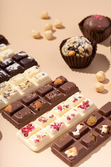 Craft white, milk and black chocolate candies on beige background flat lay, top view