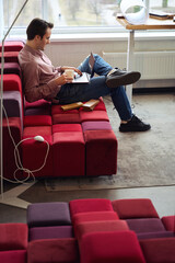 Young interior designer using portable computer during coffee break