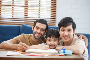 Happy cheerful LGBTQ+ lovely gay couple with their adopted child enjoy living together in living...