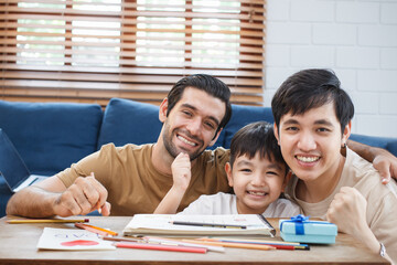 Happy cheerful LGBTQ+ lovely gay couple with their adopted child enjoy living together in living room and doing some leisure activity. Modern family and relationship lifestyle in LGBT people.