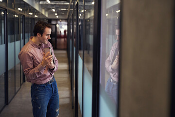 Corporate worker taking selfie with phone in empty office corridor