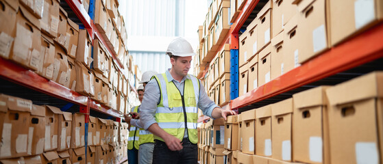 A worker in the warehouse checking the stock is on the shelves at the manufacturing. Engineer is...