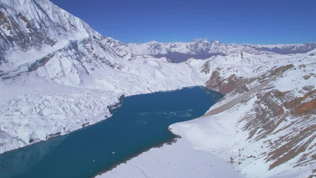 Aerial panning close up view blue Tilicho lake surrounded by snowy Himalaya mountains range in Nepal. Manang. Highest Alpine lake in the world