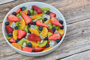 Fresh fruit salad bowl on wood grain table concept healthy food, to control weight, to lose weight