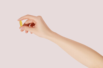 Hand holding the supplements (omega 3, vitamins) on pink background