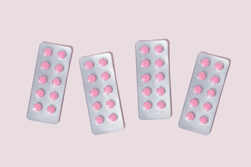 Round pink pills in blister packs on a pink background