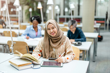 Multiethnic group of students sitting in a library and studying together
