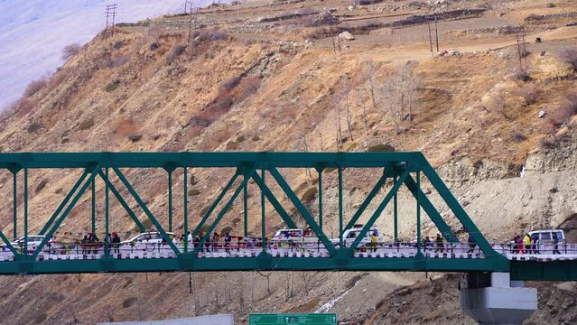 locked shot showing iron cantilever bridge over the chenab river in lahul on way to spiti with people and vehicles passing over it at the hill station