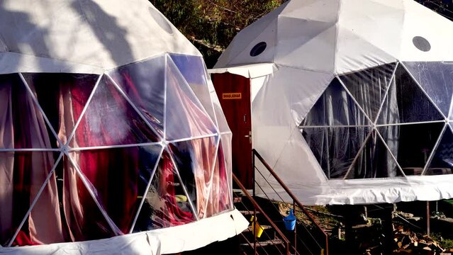 panning shot of geodesic, triangular and swiss tents at a popular glamping spot near hampta village manali for eco freindly and comfortable adventure stays
