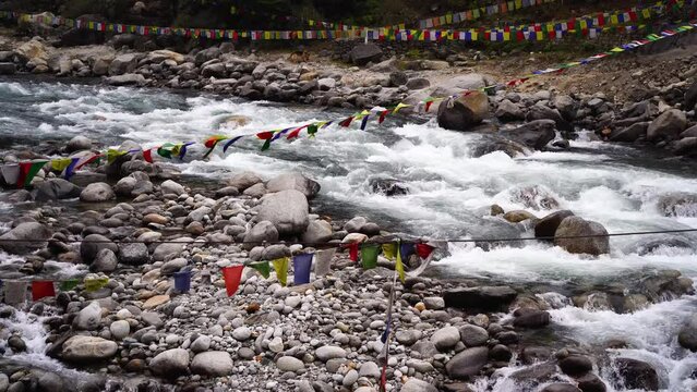 locked shot of raging beas river covered with colorful bhuddhist prayer flags put at scenic hill stations in India