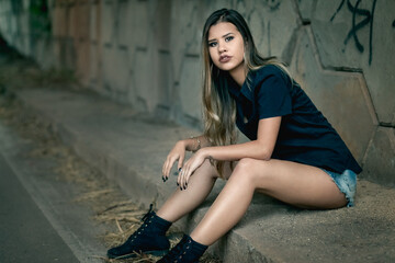 Relaxed urban fashion: serene young woman under stone overpass on city street