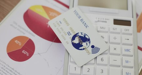 A white plastic bank card lies on a calculator, a close-up. Favorable conditions of deposit, credit history