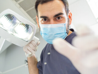 Fototapeta na wymiar Young dentist wearing a mask and gloves in a clinic during a clinical checkup