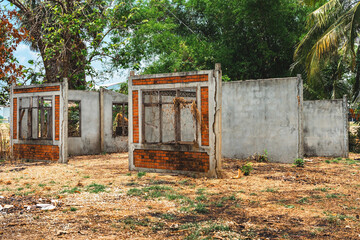 Exterior of old abandoned brick house with broken doors and windows. An unfinished and abandoned detached house. Concrete exterior of single-family house under construction in a suburban development.