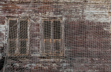 Old wooden window with shutters on the netted house wall