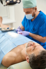 Man on operating table who is injected by doctor
