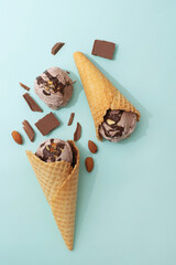Chocolate ice cream in a waffle cone, blue background, flat lay, top view, copy space. Summer cooling desserts
