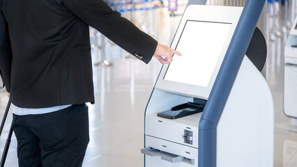 Well-dressed Businessman passenger using self service machine and help desk kiosk at airport...