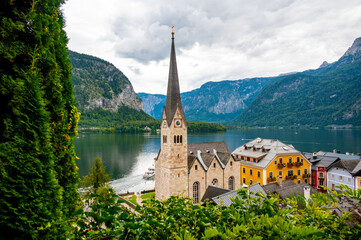 Fototapeta na wymiar Famous Hallstatt city panorama with typical church near the Hallstatter see. Dramatic clouds on the sky. Famous tourist destination in Austria.