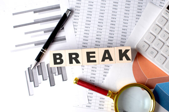 BREAK text on wooden block on graph background with pen and magnifier
