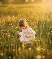 Beautiful cute little preschool girl holding a dandelion flower on the nature in the summer. Happy...