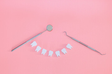 Dental tools and white toy teeth on a pink background, close-up. Dental concept banner with copy space. Children's toy doctor