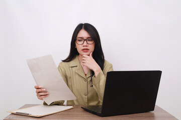 Female teacher in civil servant uniform with paper and laptop on the desk thinking something