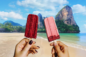 Girls eat ice lolly at a beach in Thailand