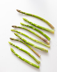 Top view crisp green asparagus on white table. Asparagus bundle in row. Vegetable pattern. Copy space.