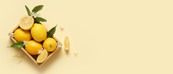 Wooden box of lemons and flowers on beige background with space for text