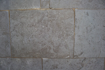 Close-up of a dark gray rectangular tile floor with wear due to time and use