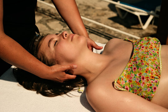 A masseur massages the lower part of a young girl's head