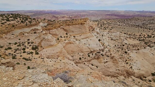 Tilt up-Rugged canyon rim at Seger's Hole in the San Rafael desert of Utah with far distant desert horizon. Desert scene dotted with scattered juniper and pinyon pine.