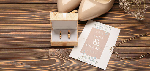 Box with wedding rings, invitation and female shoes on wooden background