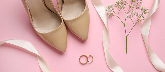Composition with wedding rings and female shoes on pink background
