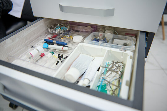 Close-up of an open drawer in a dentist's office with dental instruments, consumables and supplies used in a dental practice