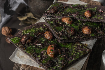 Obraz premium Halloween concept food. Flatbread or pizza with squid Ink, green cheese, mushrooms and purple onion