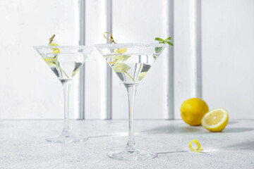 Glasses of tasty martini and lemon on white table