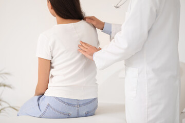 Naklejka premium Male doctor checking posture of young woman in clinic