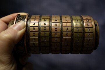 caja de rompecabezas de letras estilo código Da Vinci, sostenido por una mano, para resolver acertijo
