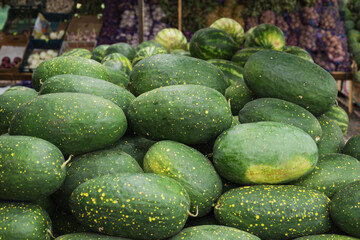 Farmers market with sweet green watermelons, open shelves of vegetables and fruits. Healthy organic food, autumn harvest. Environmentally friendly non-GMO products. Selective focus.