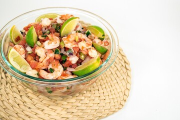 Fresh shrimp salad with lime slices in a glass bowl on a bamboo mat 