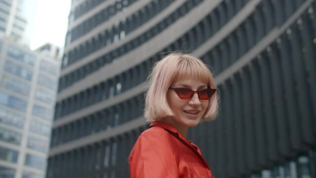 Blonde millenial woman in red in down town posing to the camera in slow motion