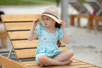 Cute adorable caucasian little kid girl enjoy having fun relaxing on sunbed on a beach. Child...