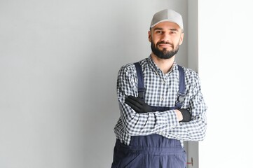 Laughing construction worker on the background of a gray concrete wall. Renovation. place for text