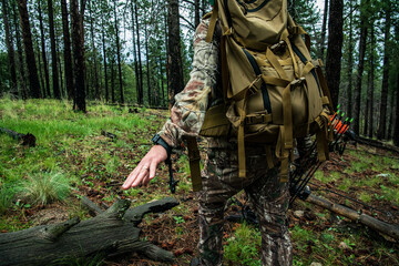 A hunter in camouflage and wearing a backpack signals quiet while bowhunting in the Valles Caldera National Preserve, New Mexico