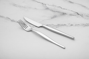 Fork and knife on white marble table, closeup