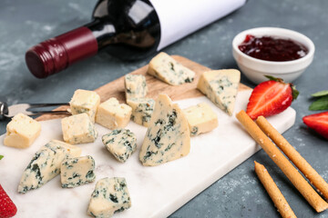 Board with pieces of tasty cheese on grey background